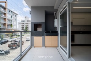 A modern apartment with a balcony, a kitchen with dark countertops, and a view of the street.