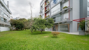 A modern apartment building with balconies, a grassy courtyard, and trees.