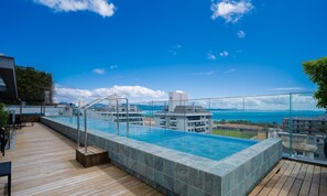 Piscina infinita en la azotea con vistas despejadas al océano y montañas distantes.
