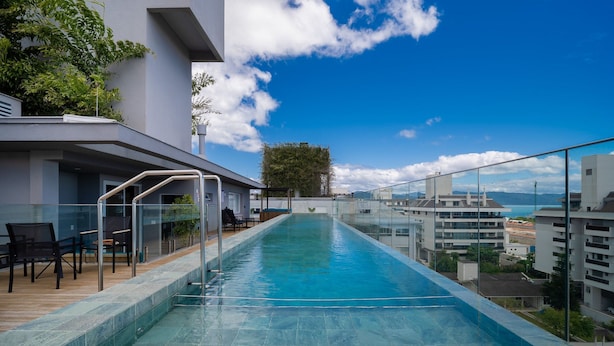 A rooftop infinity pool with a clear view of the cityscape and mountains in the distance.