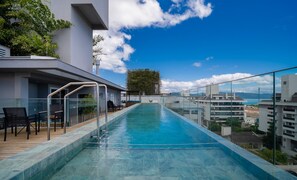 Une piscine à débordement située sur le toit, offrant une vue dégagée sur le paysage urbain et les montagnes au loin.