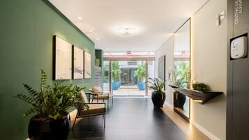Un moderno vestíbulo de hotel con una pared verde, una zona de estar y un mostrador de recepción.
