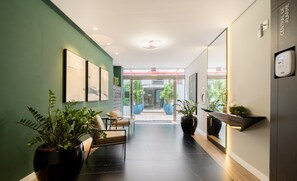 Una hall d'albergo moderna con una parete verde, un'area salotto e una reception.