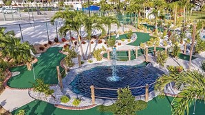 A miniature golf course with a central water feature, surrounded by landscaped areas and palm trees. - Cozy 1-bedroom resort home with 1 bathroom. Sleeps 6 using sofa beds (Sarasota)