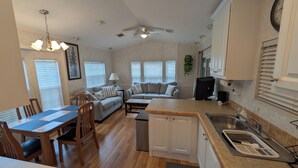 A compact living space with a dining area, sofa, kitchen, and a ceiling fan. - Cozy 1-bedroom resort home with 1 bathroom. Sleeps 6 using sofa beds (Sarasota)