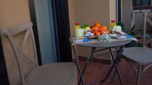Een balkon met een tafel, fruit, drankjes en een tijdschrift.