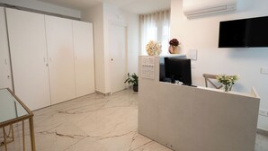 Een receptie met een balie, een flatscreen televisie, een kamerplant en een wandairconditioner.