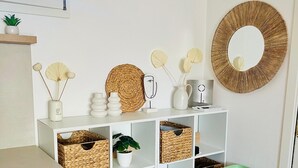 A neatly organized room with white shelving units containing wicker baskets, a green storage cart, and decorative items like a mirror and wall art. - Japandi Suites, house with garden. Oasis of relaxation 5' from the sea and the airport (Olbia)