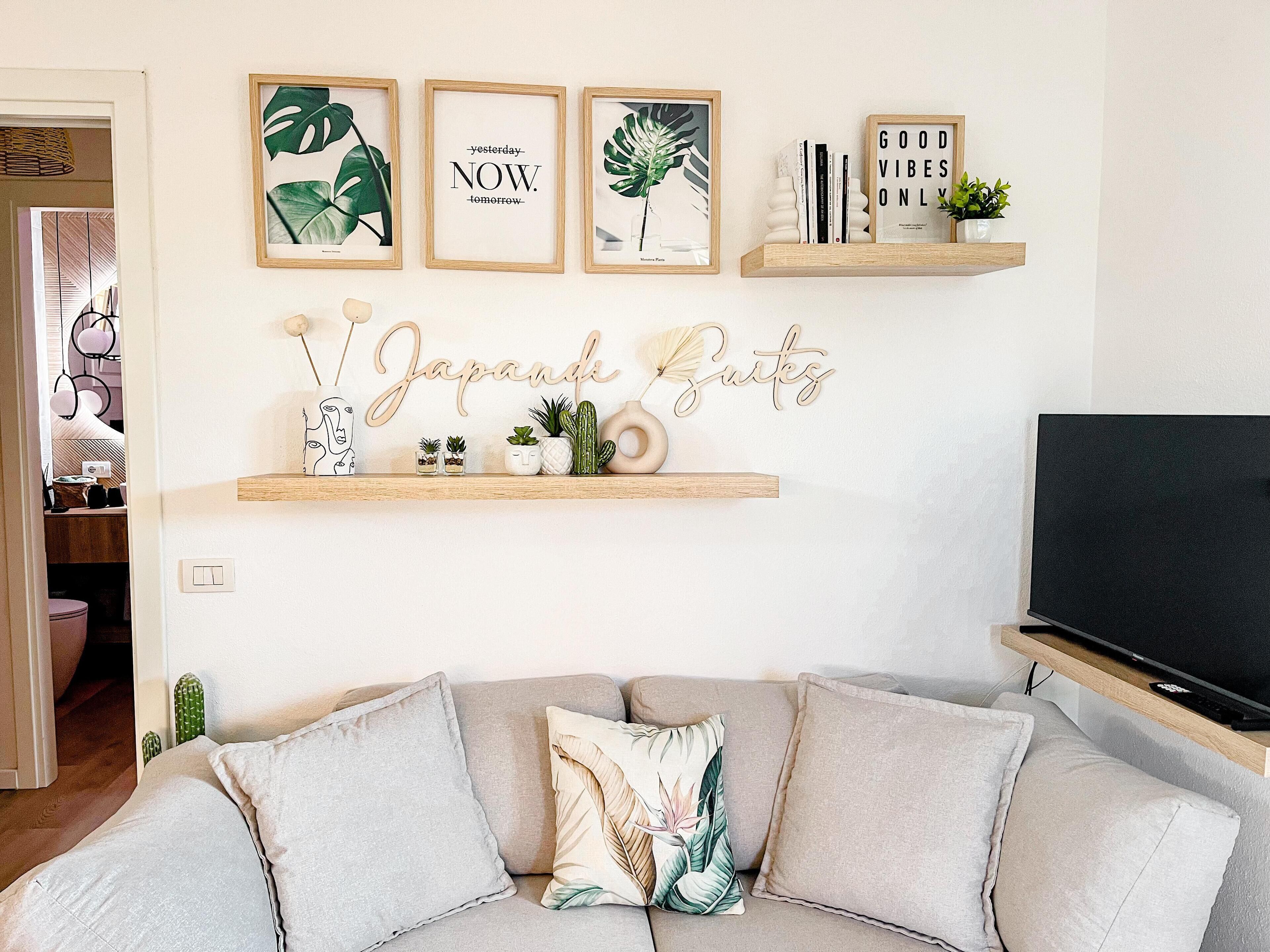 A living room with a sofa, a television, and wall decorations including framed prints and a sign.