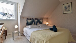 A bedroom with a bed, bedside table, lamp, and a view of the outside. - Ker Diskuizh - Proche Sentier G34 (Pléneuf-Val-André)