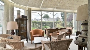 A conservatory with wicker furniture, a bookcase, and a lamp. - Ker Diskuizh - Proche Sentier G34 (Pléneuf-Val-André)
