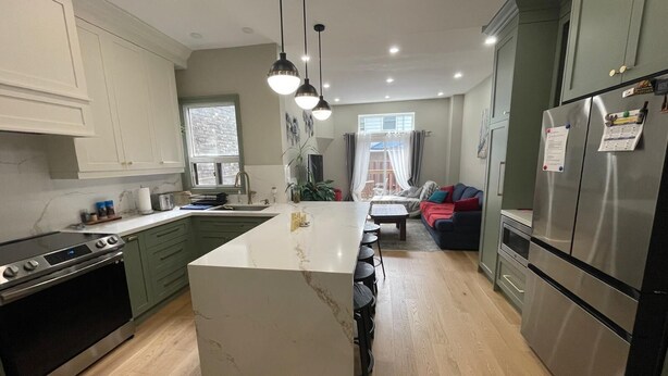 A modern kitchen with a central island, stainless steel appliances, and a dining area with a sofa. - 
World Cup Toronto Stay | Stylish 2BR in Roncesvalles/Easy Transit BMO/Yard/BBQ (Toronto)