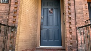 A brick building with a dark blue door, a number "32" sign, and a small window above the door. - 
World Cup Toronto Stay | Stylish 2BR in Roncesvalles/Easy Transit BMO/Yard/BBQ (Toronto)