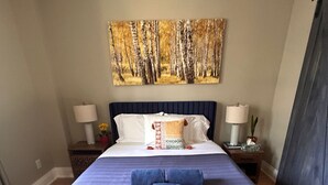 A bedroom with a large bed, a painting on the wall, and two bedside tables with lamps. - 
World Cup Toronto Stay | Stylish 2BR in Roncesvalles/Easy Transit BMO/Yard/BBQ (Toronto)