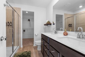 A modern bathroom with a glass shower enclosure, a white toilet, and a vanity with a large mirror. - Modern Country Escape - 5 Min to NIU (Malta)