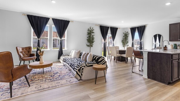 Un salon moderne comprenant un canapé, des fauteuils, une table basse et un coin cuisine avec un bar.
