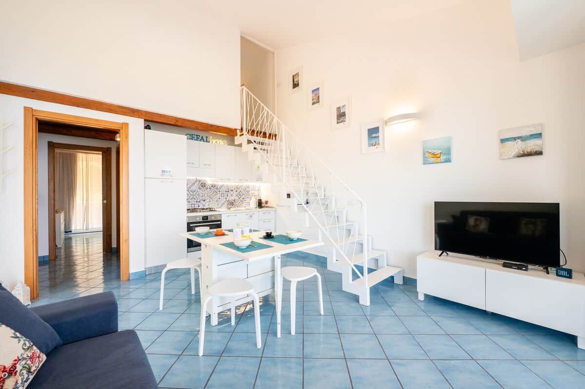 A modern living space with a kitchen, dining area, and a staircase.