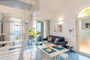 A bright room with a dining table, a sofa, and a view of the outdoors. - CefalHome - Magarà (Sicilia)