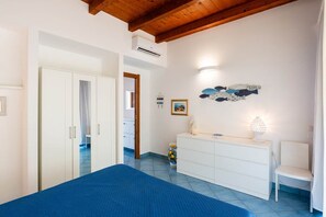 A bedroom with a bed, a white dresser, a chair, and a wall with decorative items. - CefalHome - Magarà (Sicilia)