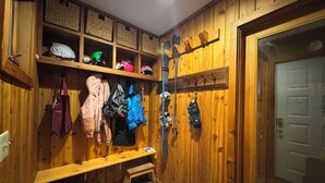 A wooden locker room with shelves, hooks, and a bench.