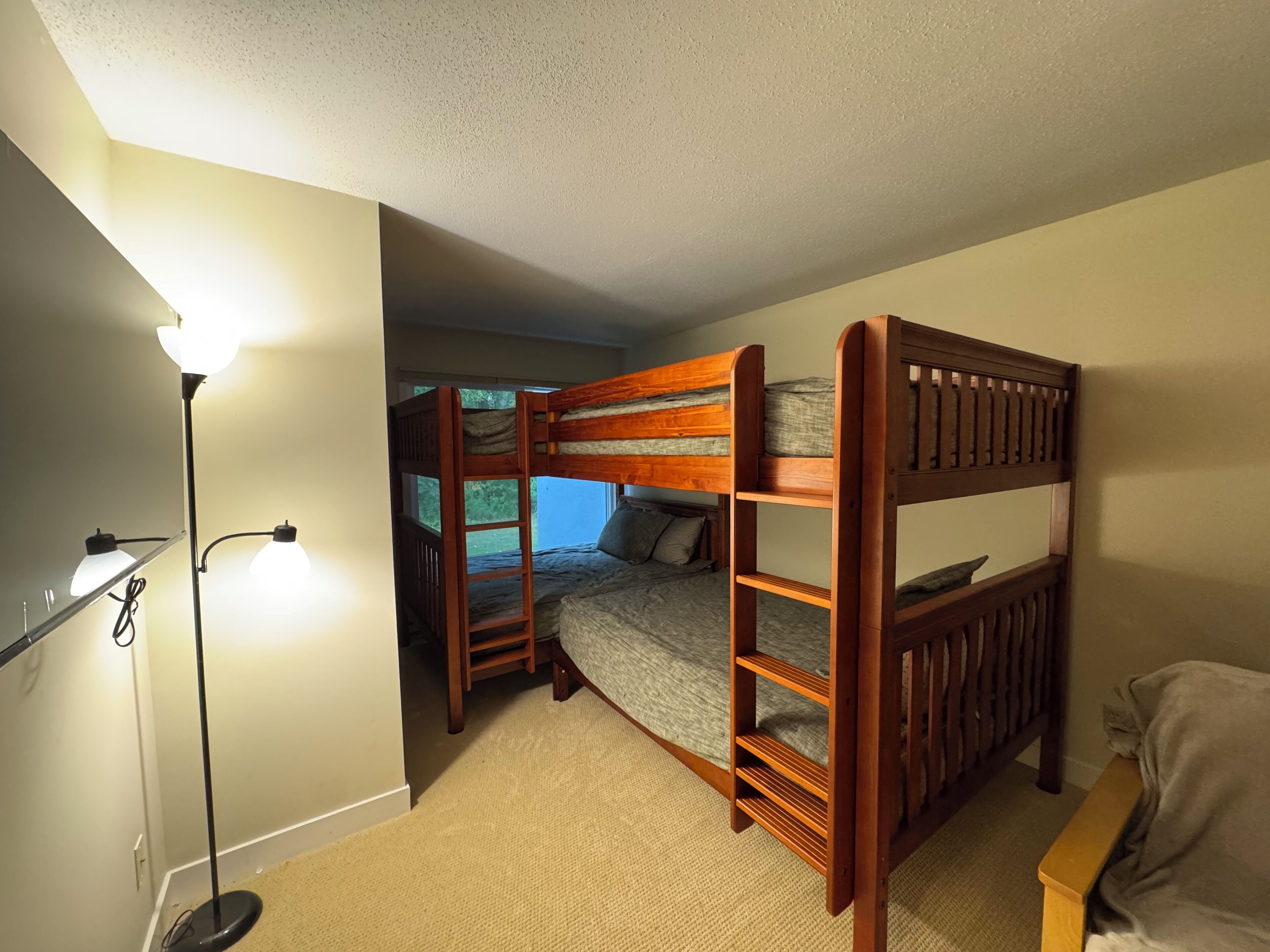 A bunk bed room with a desk and a lamp.