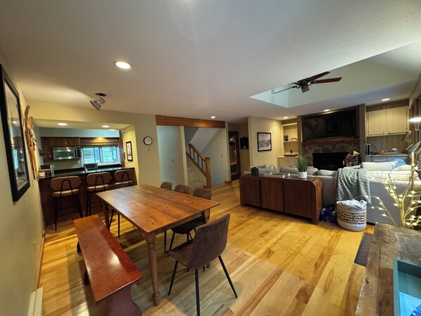 A spacious living area with a wooden dining table, a sofa, and a fireplace. - Beautiful townhome in charming Stratton for your relaxing getaway. (Stratton)