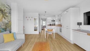 Een moderne keuken met witte kasten, een houten aanrechtblad en een eethoek met tafel en stoelen.