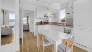 Een moderne keuken met witte kasten, een centraal eiland en een eethoek met twee stoelen.
