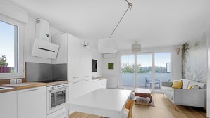 Een moderne keuken met witte kasten, een inbouwoven en een groot raam.