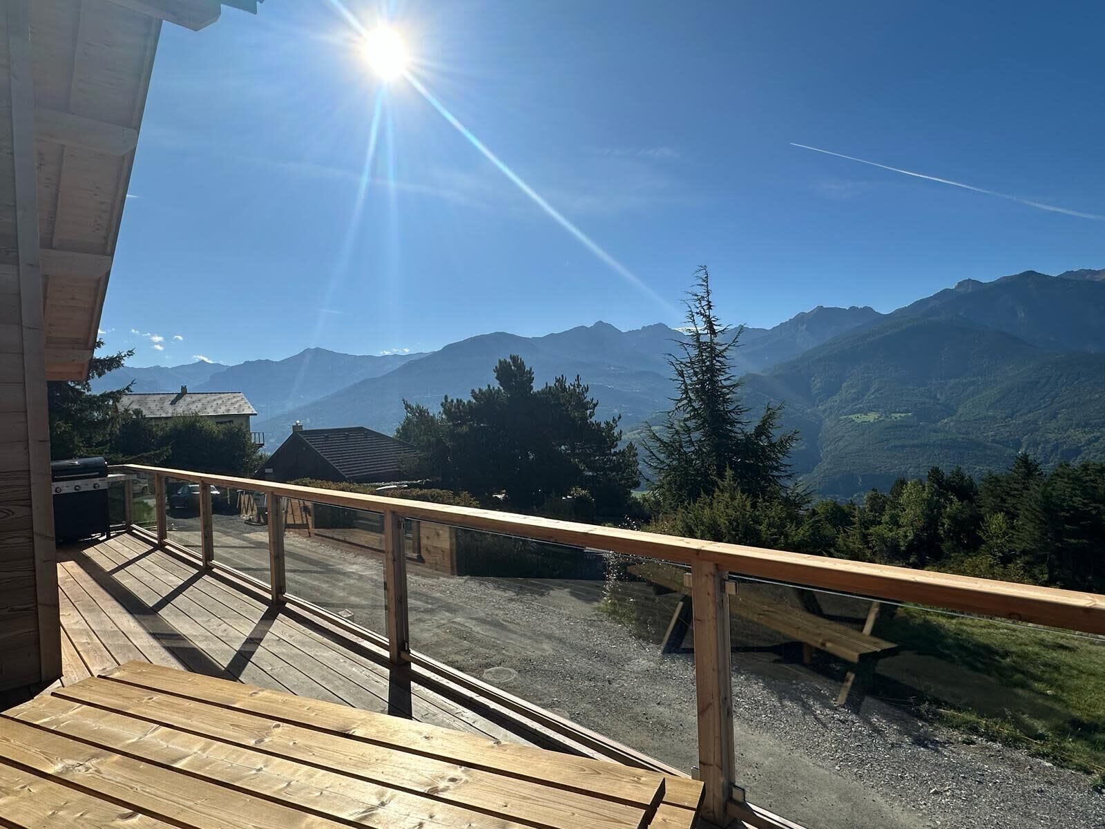 Une terrasse en bois dotée d’une balustrade, d’où l’on peut admirer un paysage montagneux.