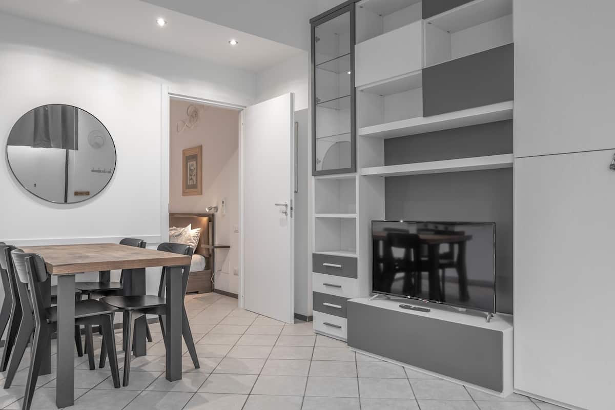 A modern kitchen with a dining table, chairs, a TV, and built-in shelving.