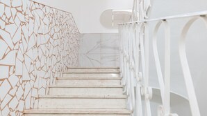 Een trap met witte leuningen en een muur met een geometrisch patroon.