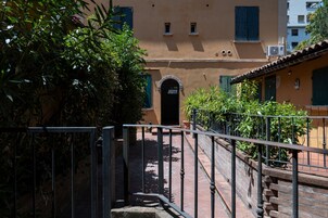 Un viuzza stretta con una ringhiera metallica, un muro in mattoni e un edificio con una porta e finestre.