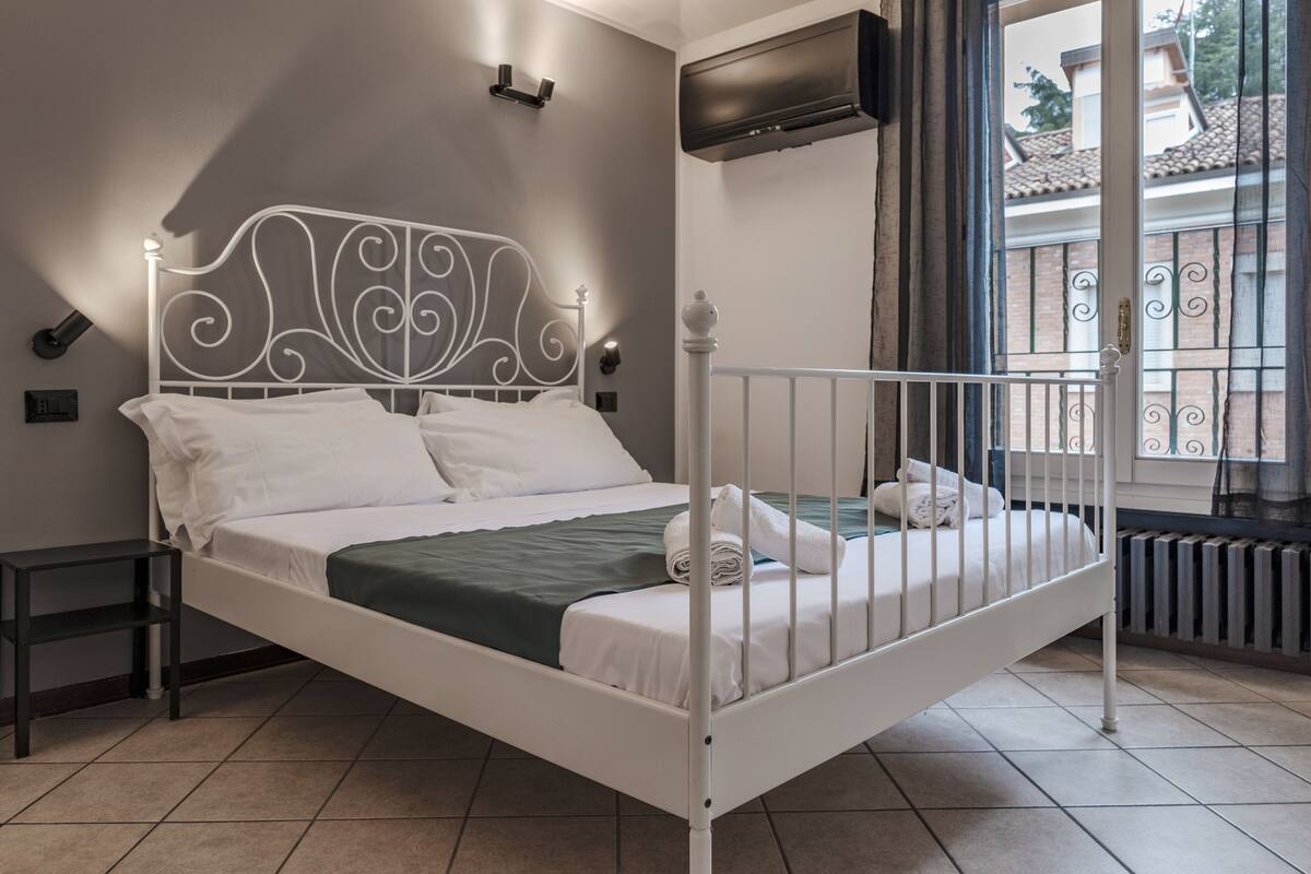 A white metal bed with a decorative headboard, a green blanket, and white bedding.