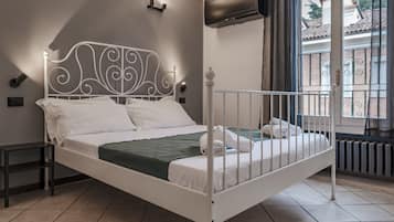 A white metal bed with a decorative headboard, a green blanket, and white bedding.
