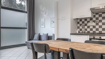 A modern kitchen with a checkered backsplash, a wooden dining table, and a gray sofa.