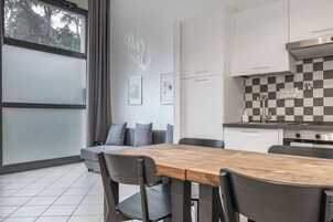 Una cucina moderna con zoccolo a scacchi, un tavolo da pranzo in legno e un divano grigio.