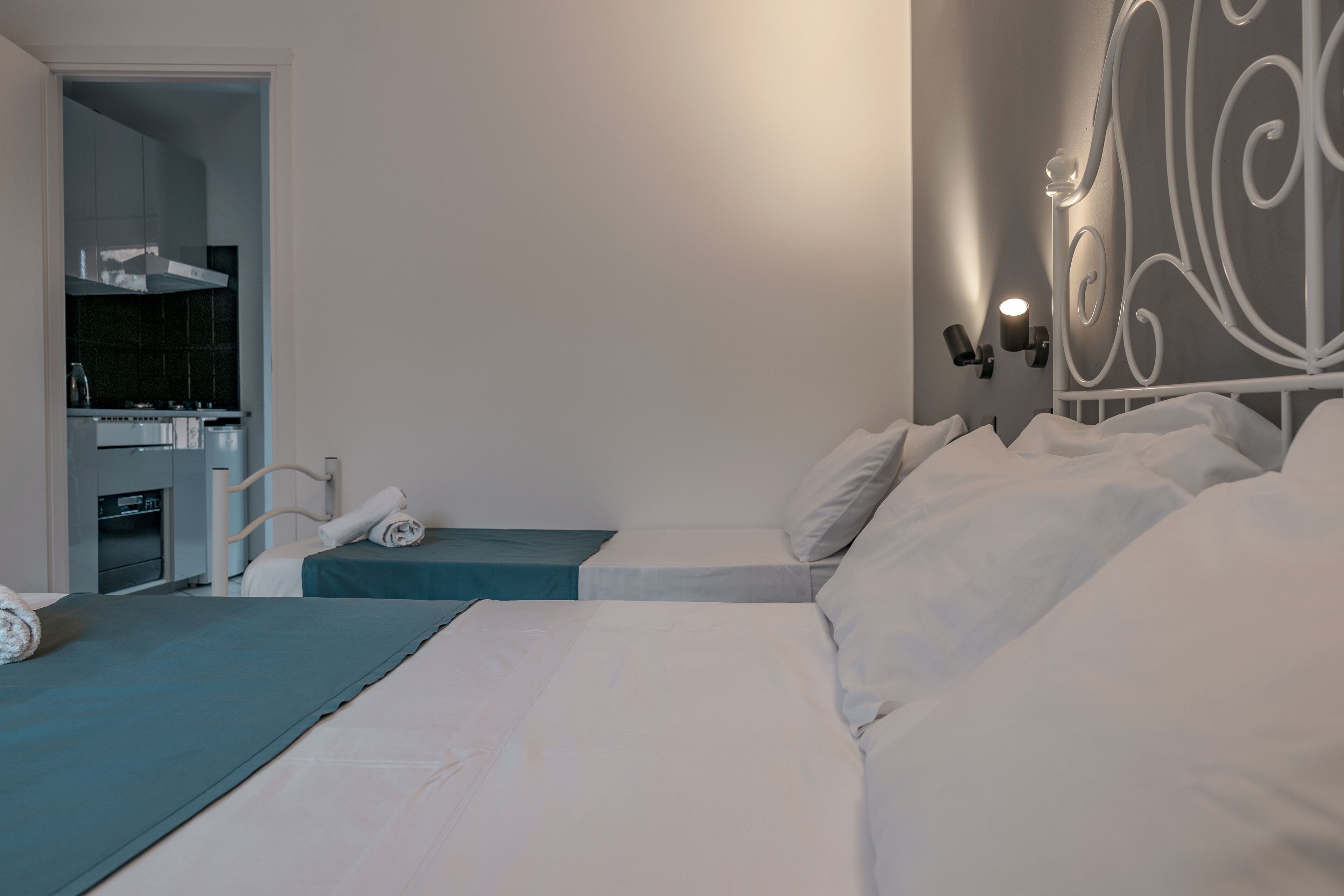 Une chambre avec deux lits, un coin cuisine et un mur décoratif.