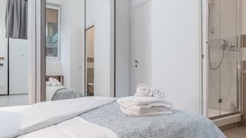 A hotel room with a bed, a bathroom with a shower, and a view of the outside.