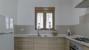 Une cuisine avec un plan de travail en bois, un évier, une fenêtre avec des rideaux, une cuisinière et un four à micro-ondes.