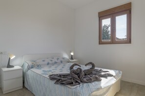 Une chambre à coucher avec un lit, deux tables de chevet avec des lampes, une fenêtre et une vue sur l’extérieur.