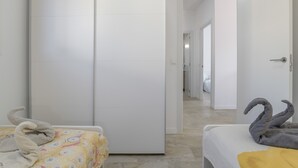 Une chambre d’hôtel comprenant un lit, une armoire et un couloir menant à une autre pièce.