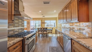 A kitchen with wooden cabinets, a granite countertop, a stove, and a dishwasher. - Walk to beach, 3/2 w/Views, Deck & Accessibility (Cayucos)