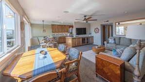 A spacious living room with a dining area, kitchen, and a large window. - Walk to beach, 3/2 w/Views, Deck & Accessibility (Cayucos)