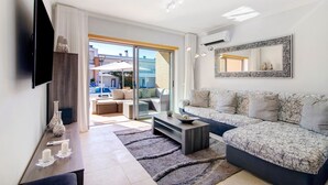 Un salon moderne avec un canapé, une table basse, un téléviseur à écran plat et un grand miroir.