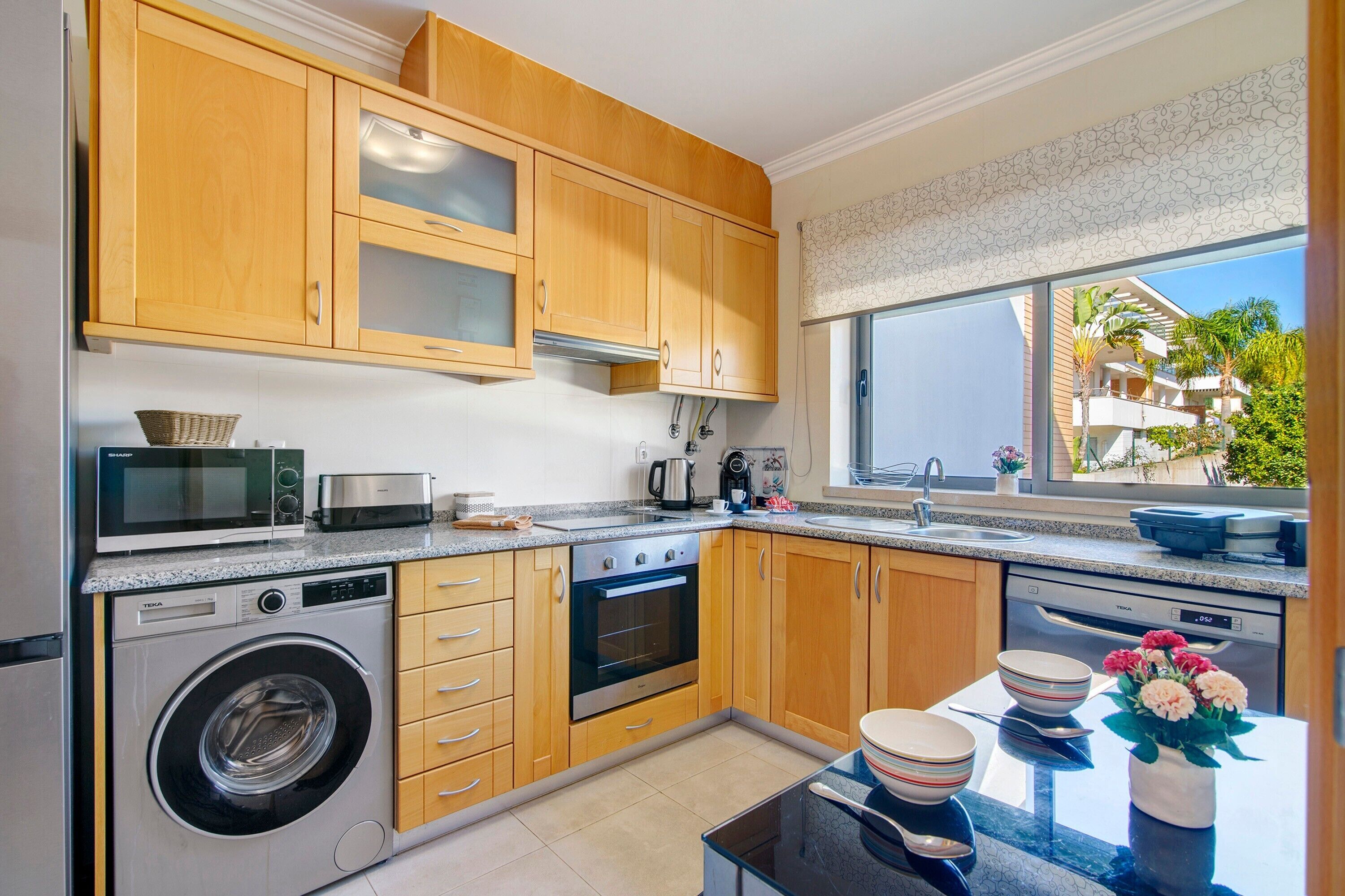 Une cuisine moderne avec des meubles en bois, un lave-linge, un four et un lave-vaisselle.