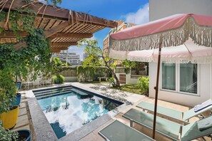 A swimming pool with lounge chairs, a pergola with climbing plants, and a covered seating area. - Condado Flat Swimming Spot Garden Haven (San Juan)