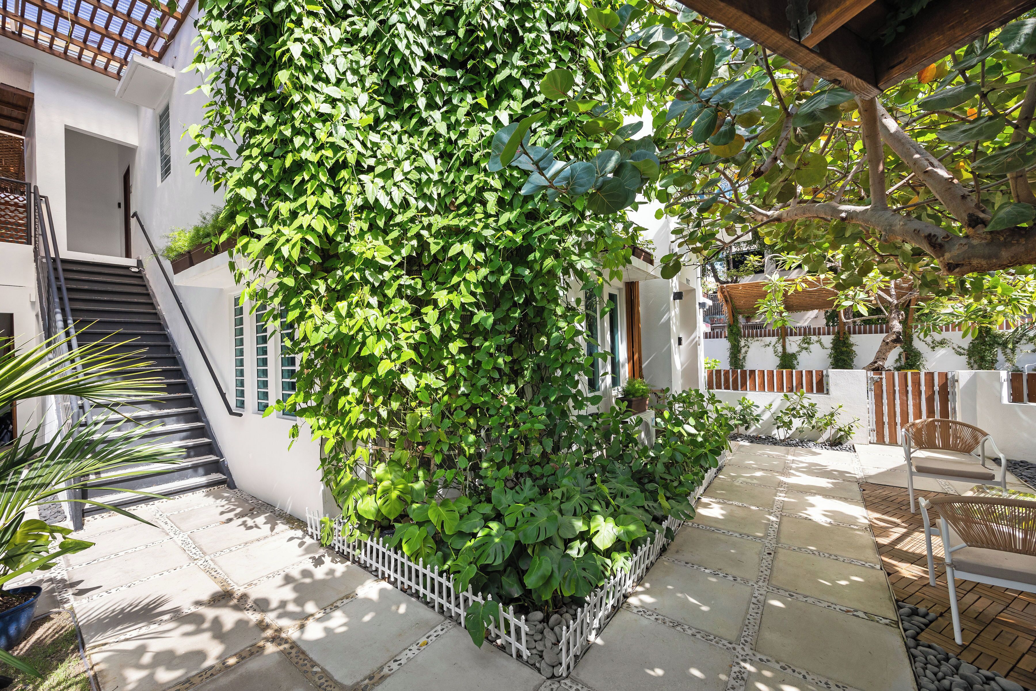 A courtyard with a white fence, a wooden staircase, and a seating area with chairs. - Condado Flat Swimming Spot Garden Haven (San Juan)