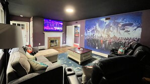 A living room with a fireplace, a large TV, and a mural. - Movie Magic: The Scene-Stealer (Winston-Salem)