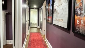 A hallway with a red carpet, posters on the walls, and a door at the end. - Movie Magic: The Scene-Stealer (Winston-Salem)